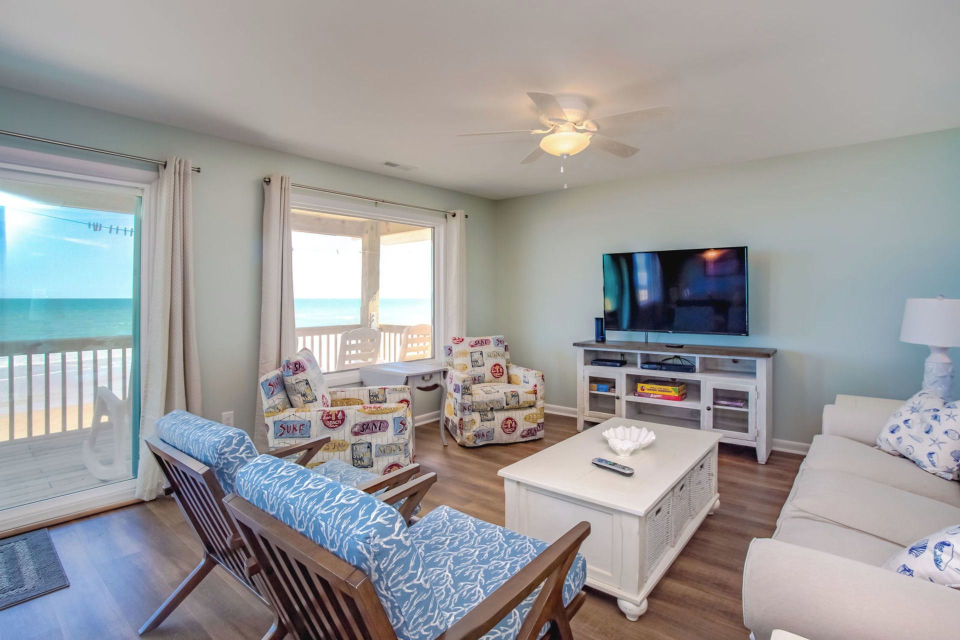 Una sala de estar con televisor, asientos y vista al océano.
