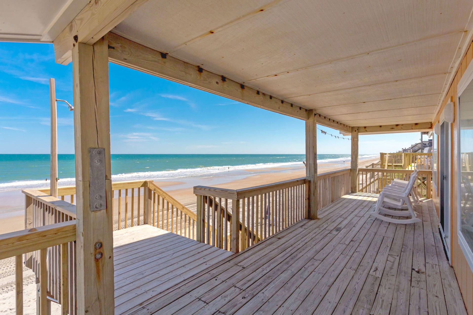 Una terraza de madera con vista a la playa y al océano.