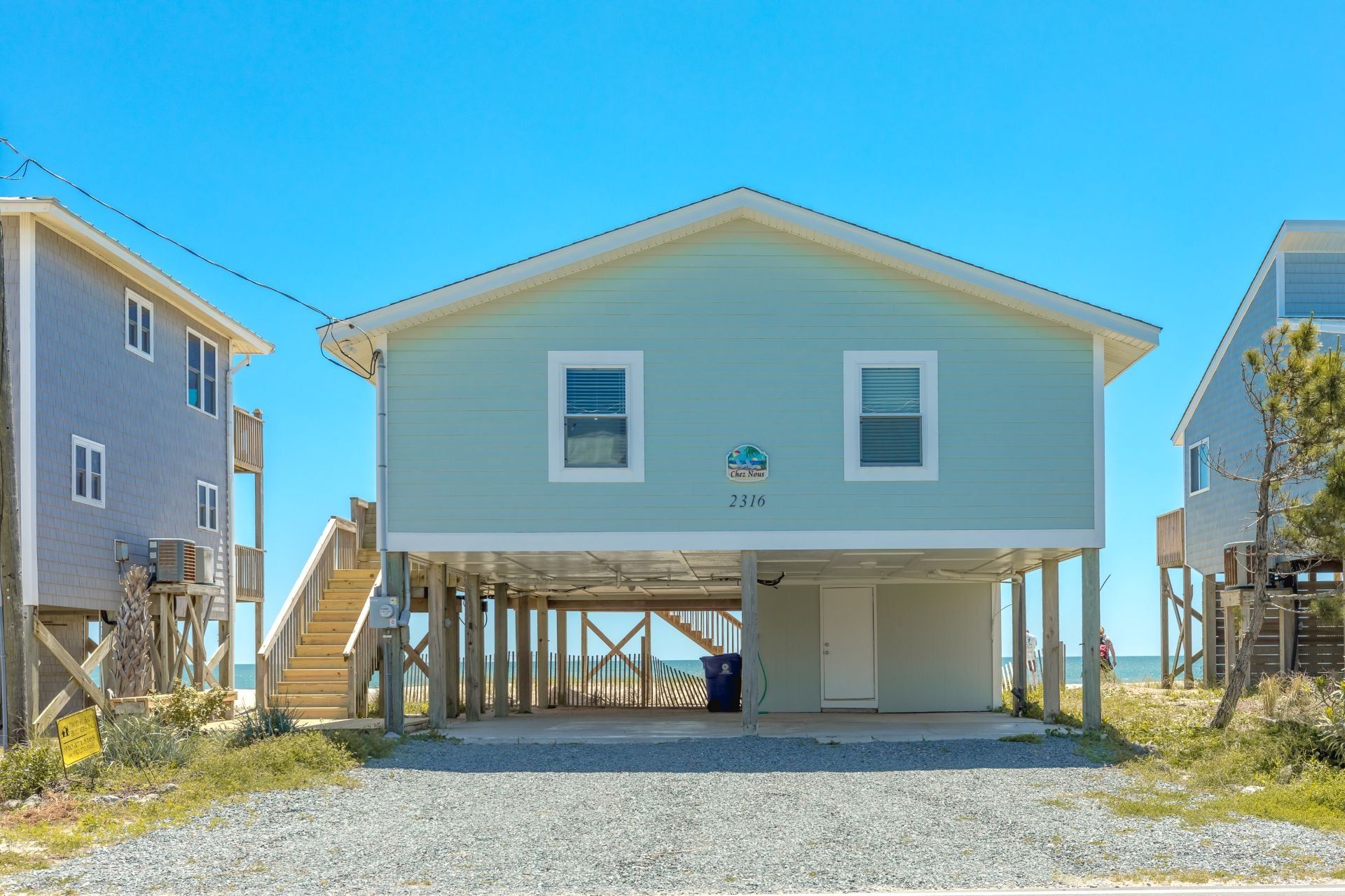 Un immeuble de deux étages doté d’une entrée couverte et d’un balcon, situé près de la plage.