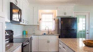 A modern kitchen with white cabinetry, a black refrigerator, a built-in oven, and a microwave. - Chez Nous - Classic 3BR Oceanfront Home with Modern Updates (Surf City)