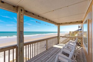 A wooden deck with a view of the beach, a thermometer, and a string of lights. - Chez Nous - Classic 3BR Oceanfront Home with Modern Updates (Surf City)