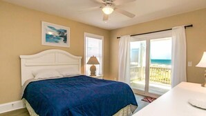 A bedroom with a bed, a ceiling fan, a window with curtains, and a view of the beach. - Dakota Dunes - Oceanfront!  Dog Friendly! (Surf City)