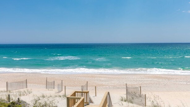 A beach with a wooden structure and a fence. - Dakota Dunes - Oceanfront!  Dog Friendly! (Surf City)