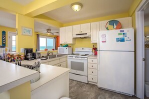 A kitchen with white cabinets, a stove, a microwave, and a refrigerator.