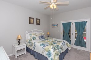 A bedroom with a bed, two wall-mounted lamps, a ceiling fan, and a door with curtains. - Dettor - Oceanfront, Dog Friendly! (Topsail Beach)
