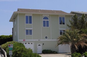 En toetages bygning med garage, nummer 201, og et skilt der viser adgang til offentlig strand.