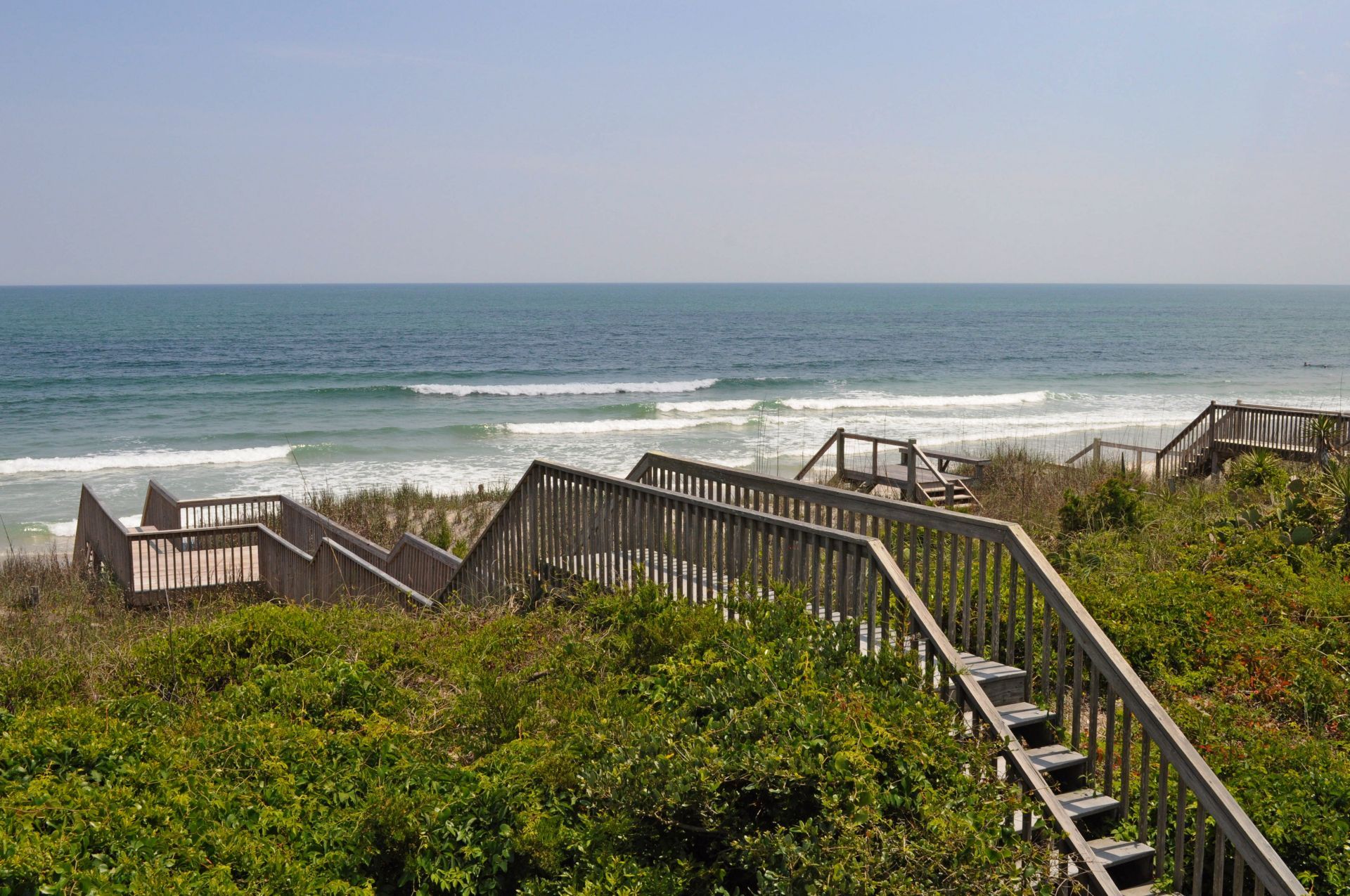 A wooden staircase leading to a beach with ocean views.