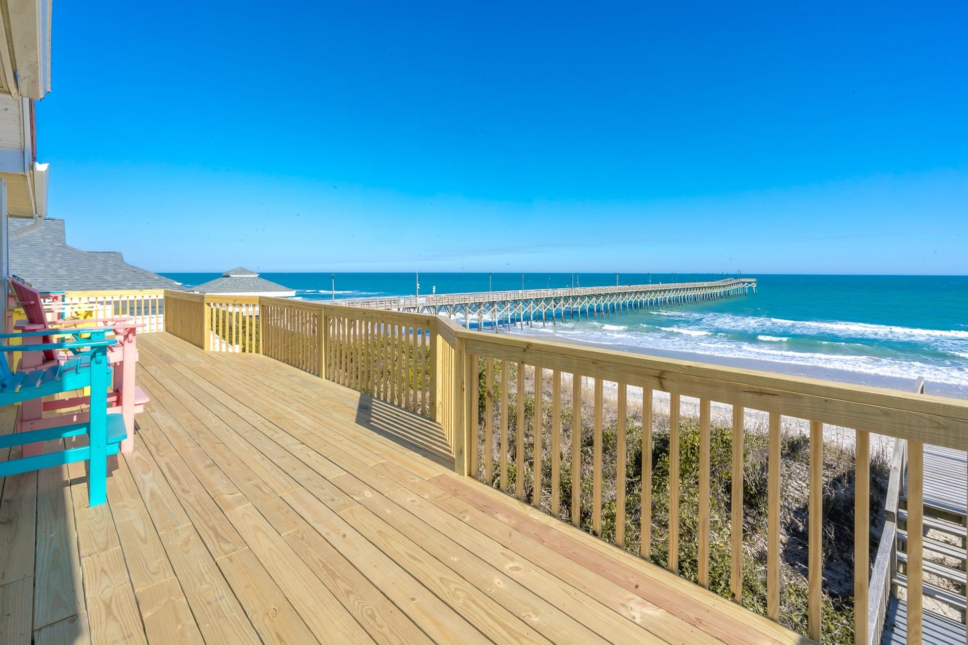 A wooden deck with a view of the ocean and a pier.