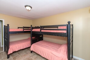 A room with three bunk beds, each with a pink mattress, and a ceiling light fixture. - Double U Seas - Oceanfront, Dog & Cat Friendly! (Surf City)