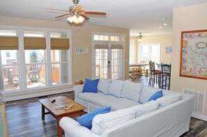 A living room with a sofa, a coffee table, and a dining area with chairs and a table.
