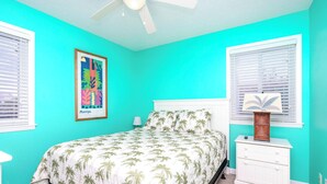 A bedroom with a bed, a ceiling fan, a framed picture on the wall, and a nightstand with a lamp. - Fins To The Left -Oceanfront 3 BR. (Surf City)
