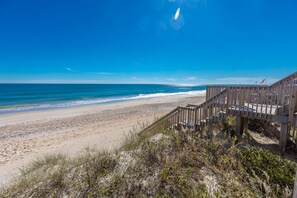 A wooden boardwalk leading to a beach with clear skies.