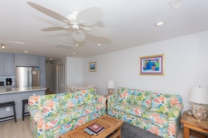 A living room with a sofa, coffee table, and a ceiling fan.