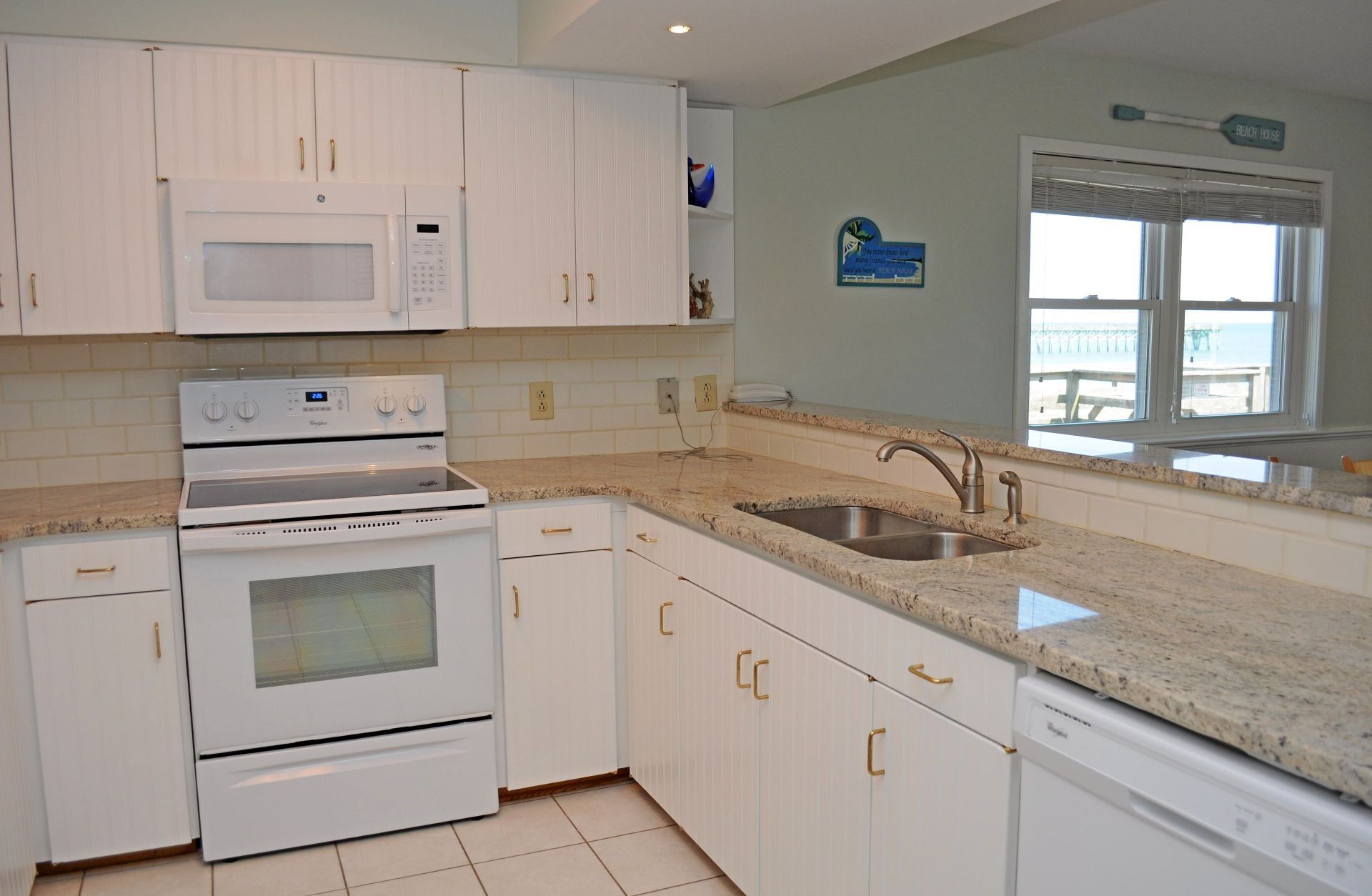 A kitchen with white cabinetry, a built-in microwave, an oven, a dishwasher, and a granite countertop.