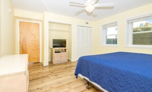 A bedroom with a bed, a ceiling fan, a television on a stand, and a window. - Oceanic: Spacious 6BR oceanfront home (Surf City)