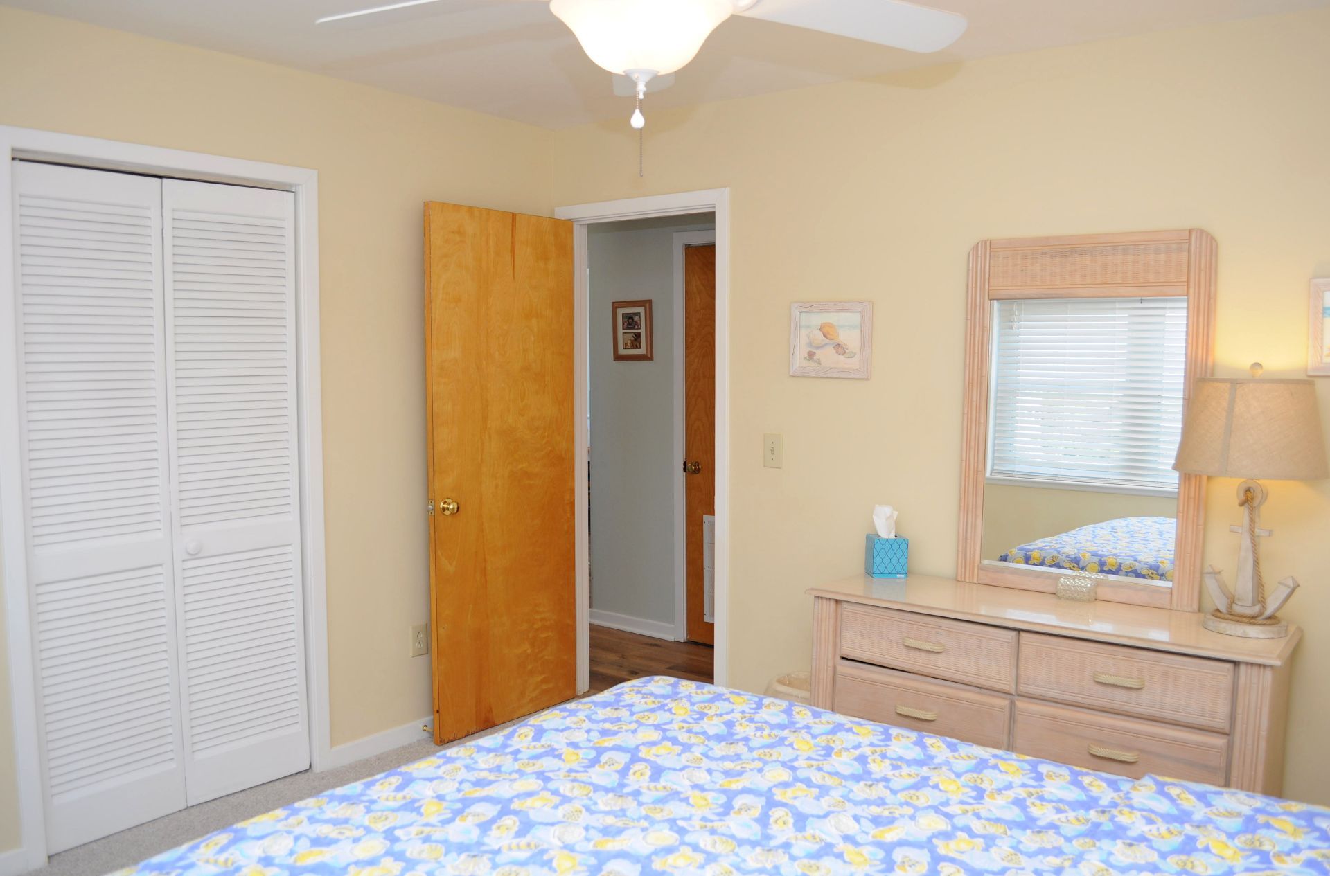 A bedroom with a bed, a dresser, a mirror, and a door leading to another room.
