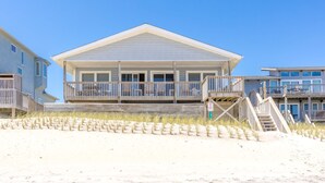 A beachfront building with a balcony, wooden deck, and a sign indicating a keep-off double line. - Our Heels in the Sand, a spacious 4-bedroom oceanfront home (Surf City)