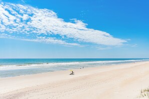 A beach with a clear sky and a few clouds.