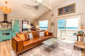 A living room with a sofa, coffee table, and a view of the beach.