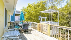 A wooden deck with outdoor furniture, a covered seating area, and a view of trees.