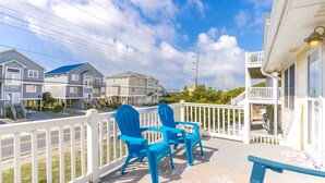 A balcony with two blue Adirondack chairs, a white railing, and a view of adjacent buildings. - Sea View - 3 bedroom, 2 bath cottage in Surf City!  Dog Friendly! (Surf City)