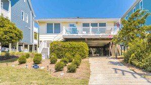 A two-story building with a balcony, a covered walkway, and a well-maintained lawn.