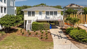 A two-story residential house with a front porch, a small garden, and a visible mailbox.