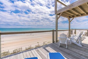 A wooden deck with beach chairs and a view of the ocean.