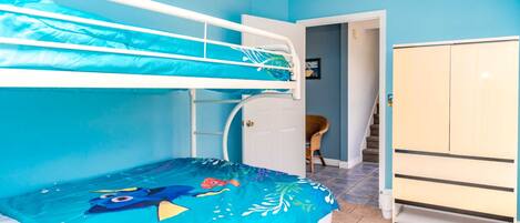 Una habitación con literas, un armario y una puerta que da a otra habitación.