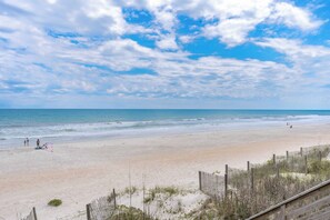 A beach with a wooden fence and a clear sky.