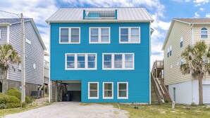 En tvåvåningsbyggnad med en blå fasad, flera fönster och en inglasad veranda.