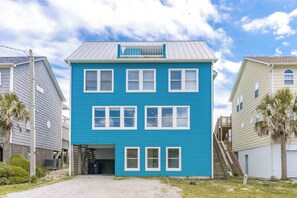 A two-story building with a blue exterior, multiple windows, and a covered front porch. - Simple Pleasure Oceanfront in Surf City, NC—perfect for 15! (Surf City)