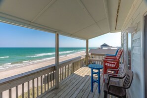 A wooden deck with a view of the beach and ocean.