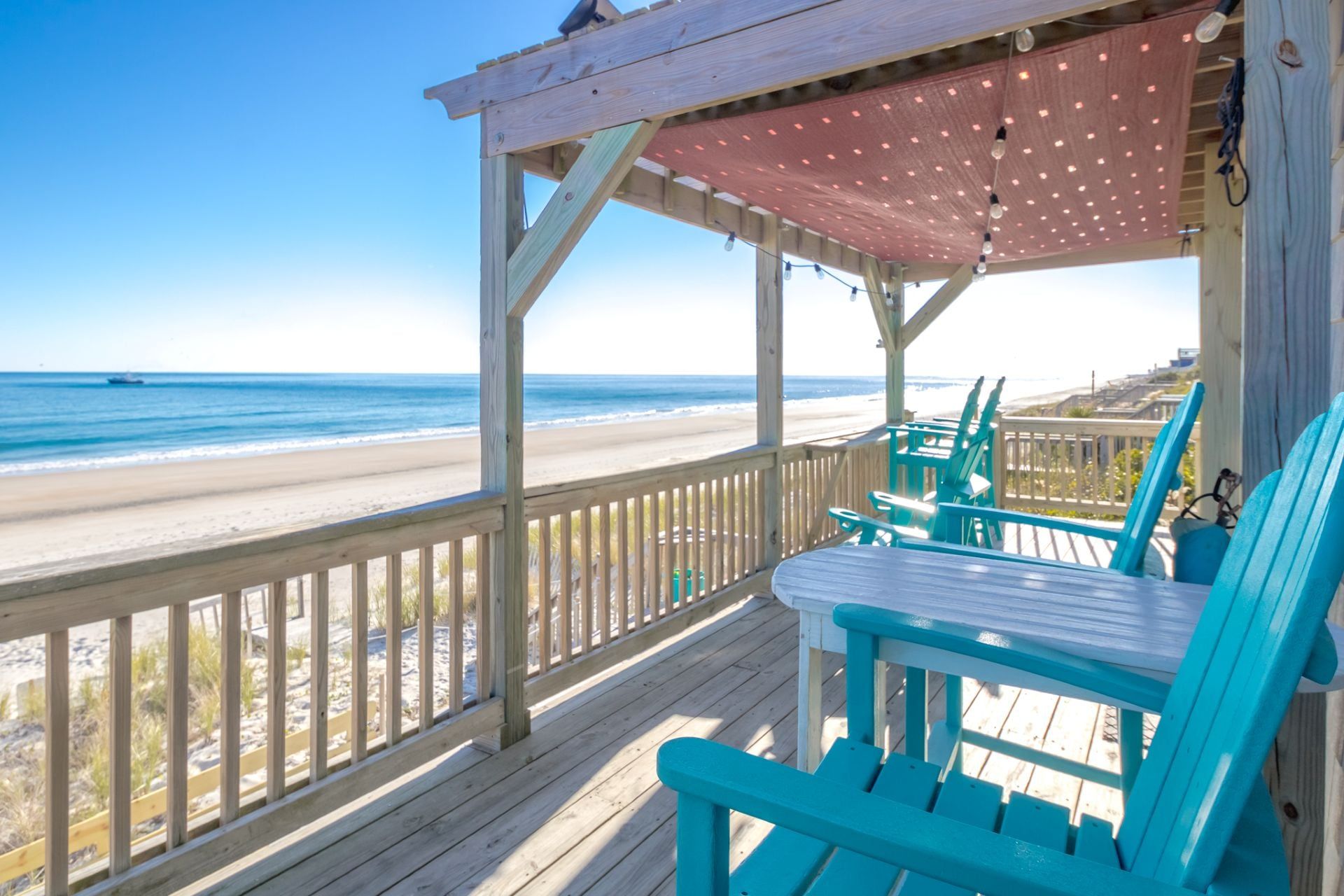 Una terraza de madera con vista a la playa y al océano.