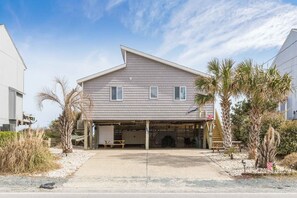 A two-story house with a garage, surrounded by palm trees and a gravel driveway. - Surf Club - Oceanfront, 3 bedroom, gorgeous home in Surf City!  Dog Friendly! (Surf City)