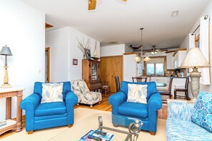 A living room with two blue sofas, a coffee table, and a dining area with a table and chairs.