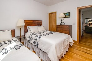 Una camera da letto con un letto, comodini, una cassettiera e una porta che dà su un'altra stanza.