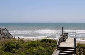 Una passerella in legno che conduce alla spiaggia, con le onde che si infrangono sulla riva.
