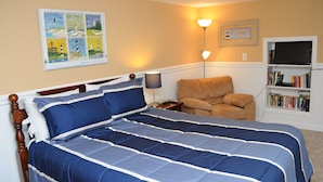 A bedroom with a bed, a chair, a bookshelf, and a painting on the wall. - Tumble Inn - Oceanfront home in Topsail Beach! Gazebo & Dog Friendly! (Topsail Beach)