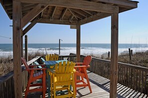 A wooden deck with a covered seating area overlooking the ocean.
