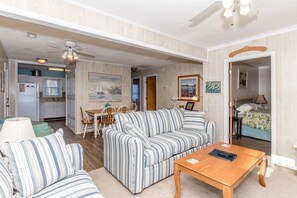 A living room with a striped sofa, a wooden coffee table, and a dining area with a table and chairs.