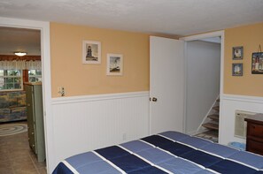 A bedroom with a bed, a door leading to a staircase, and a wall with framed pictures. - Tumble Inn - Oceanfront home in Topsail Beach! Gazebo & Dog Friendly! (Topsail Beach)