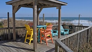 A wooden deck with a gazebo and colorful Adirondack chairs overlooking the beach. - Tumble Inn - Oceanfront home in Topsail Beach! Gazebo & Dog Friendly! (Topsail Beach)