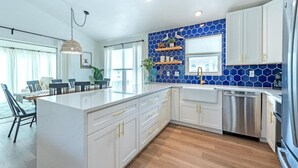 Una cocina moderna con armarios blancos, un salpicadero azul hexagonal y una isla central.