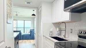 A modern kitchen with white cabinetry, a built-in oven, and a stainless steel range hood. - OD tower II #12, ocean view Fantastic condo + pool (Myrtle Beach)