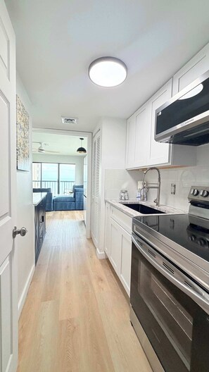 A modern kitchen with white cabinetry, a built-in oven, and a stainless steel range hood. - OD tower II #12, ocean view Fantastic condo + pool (Myrtle Beach)