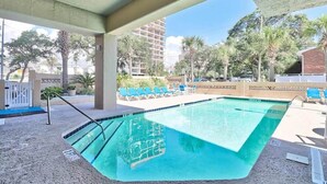 A swimming pool with a tiled deck, lounge chairs, and a covered area with a concrete ceiling. - OD tower II #12, ocean view Fantastic condo + pool (Myrtle Beach)
