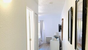 A hallway with a white door, a white bench, and a black trash bin. - Ocean Dunes Villas #22, stay close to the ocean (Myrtle Beach)