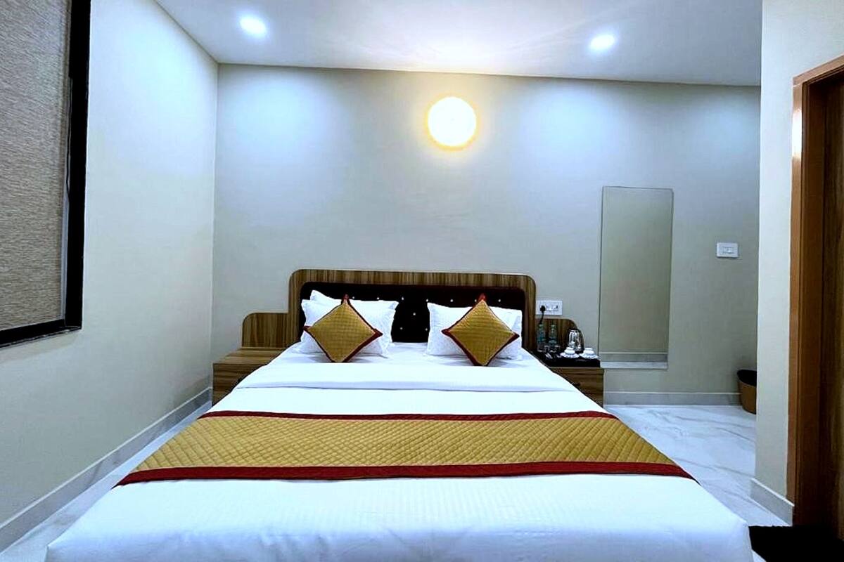 Hotelkamer met een groot bed, nachtkastje en een wandlamp.