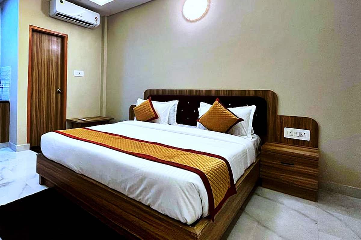 Een hotelkamer met een bed, houten nachtkastjes, een nachttafel, een kledingkast en een airconditioning.